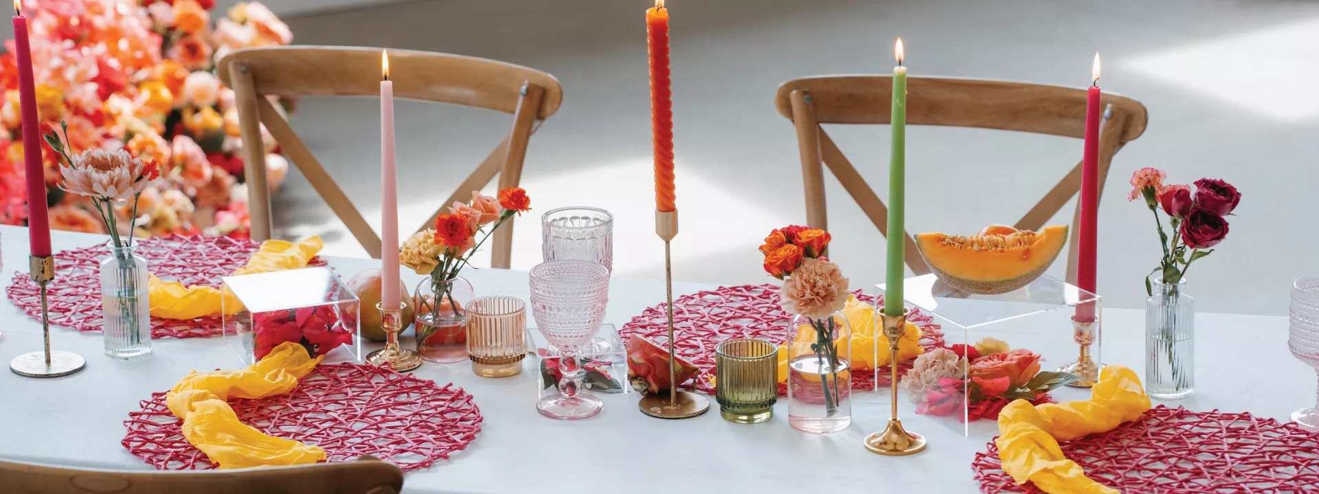 Vibrant tablescape featuring juicy hued florals, fruit accents and taper candles at Woodhaven