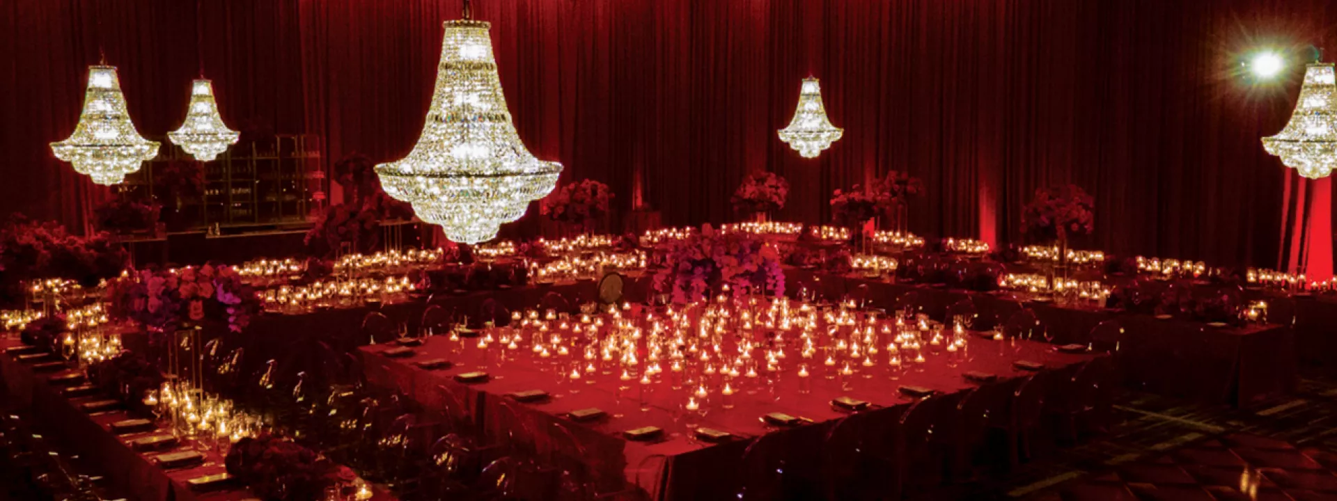 Luxe deep red reception design featuring chandeliers, candlelight, draping and a square shaped table arrangement at The Four Seasons Minneapolis