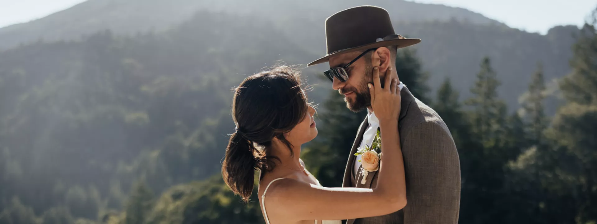 Sang and Alek embrace in their wedding attire in front of a mountainous landscape at a private residence in San Francisco Bride and groom embrace in their wedding attire in front of a mountainous landscape at a private residence in San Francisco