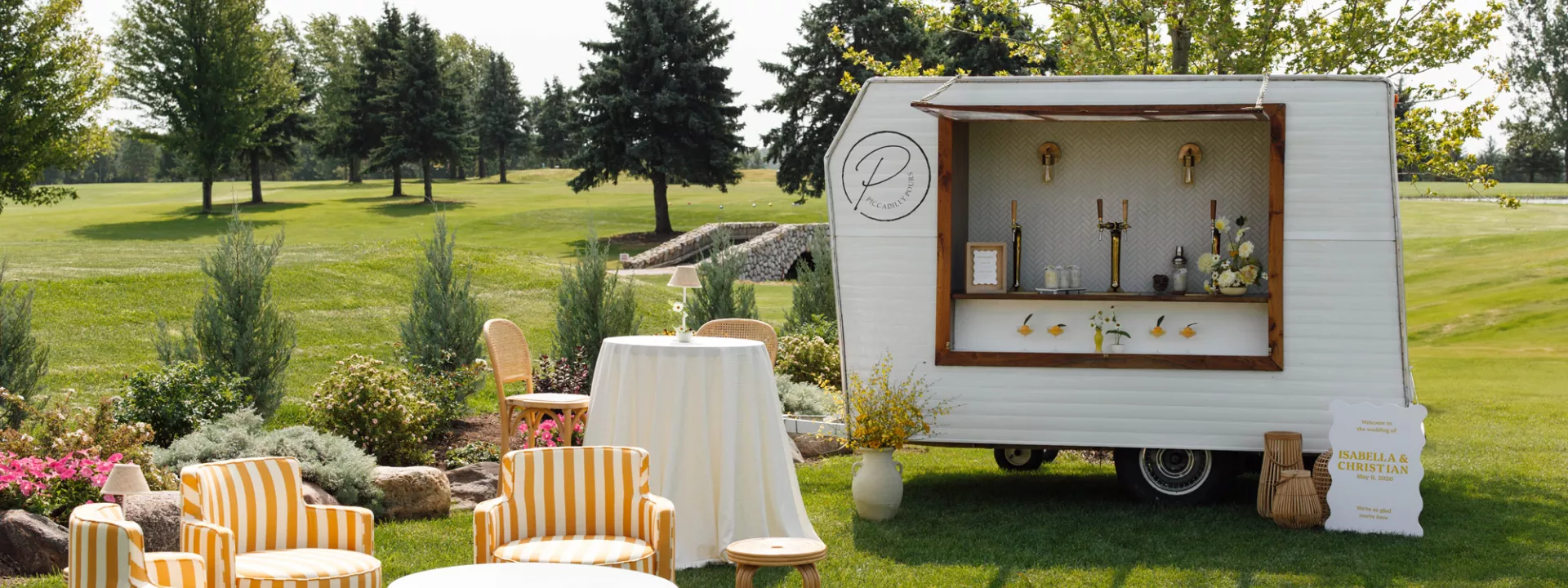 Sunny outdoor happy hour scene with yellow striped furniture and mobile bar at the Wexford at Emerald Greens