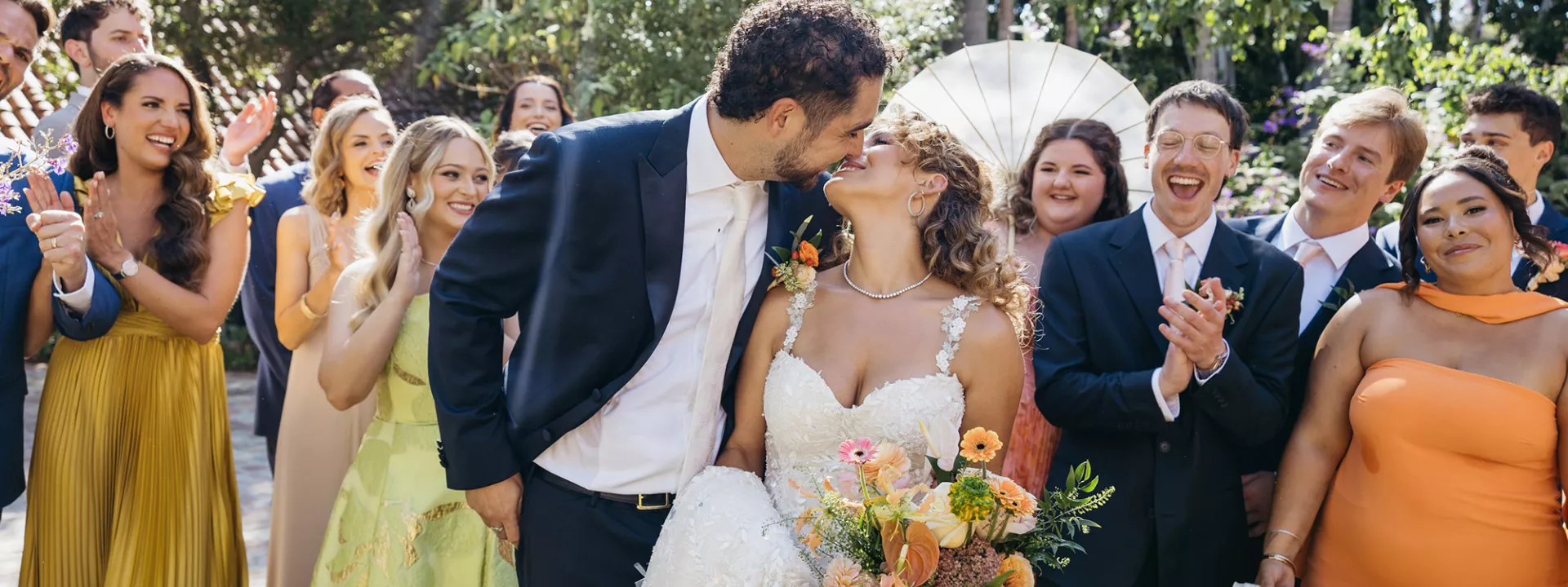 Rachel and Stefano share a kiss with their wedding party around them at private residence in San Juan Capistrano wedding day
