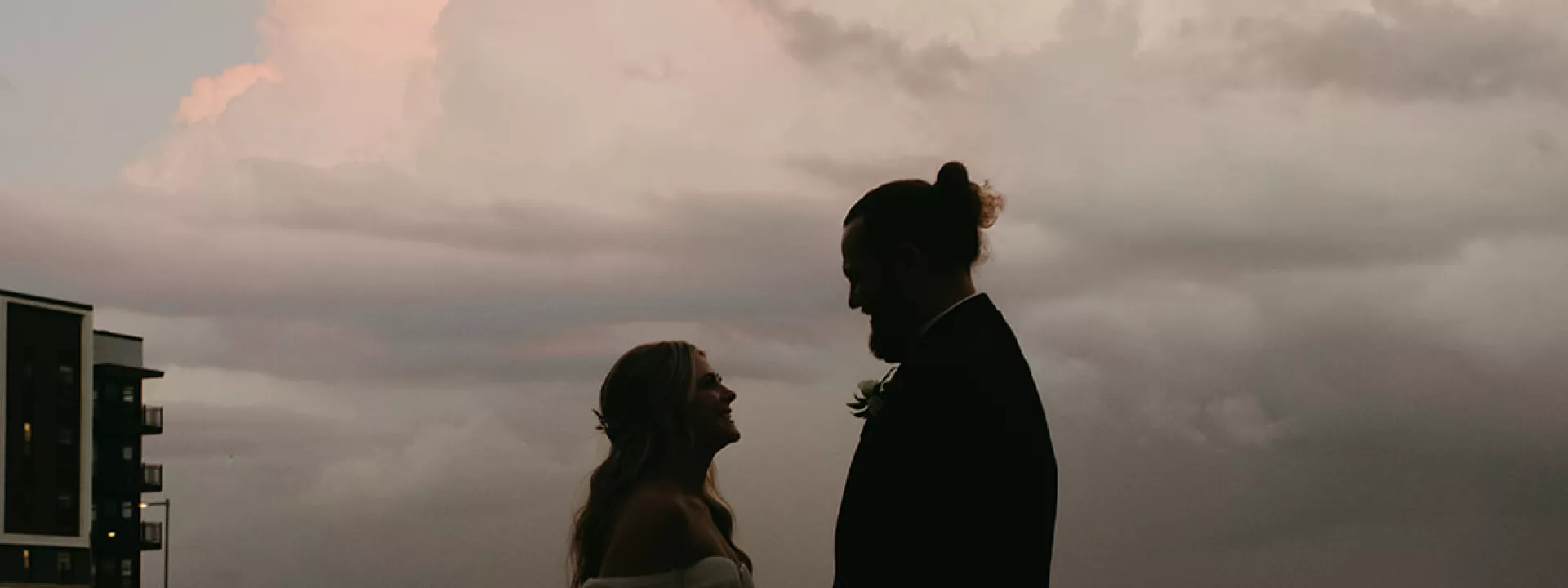 bride and groom backlit by stormy clouded sunset
