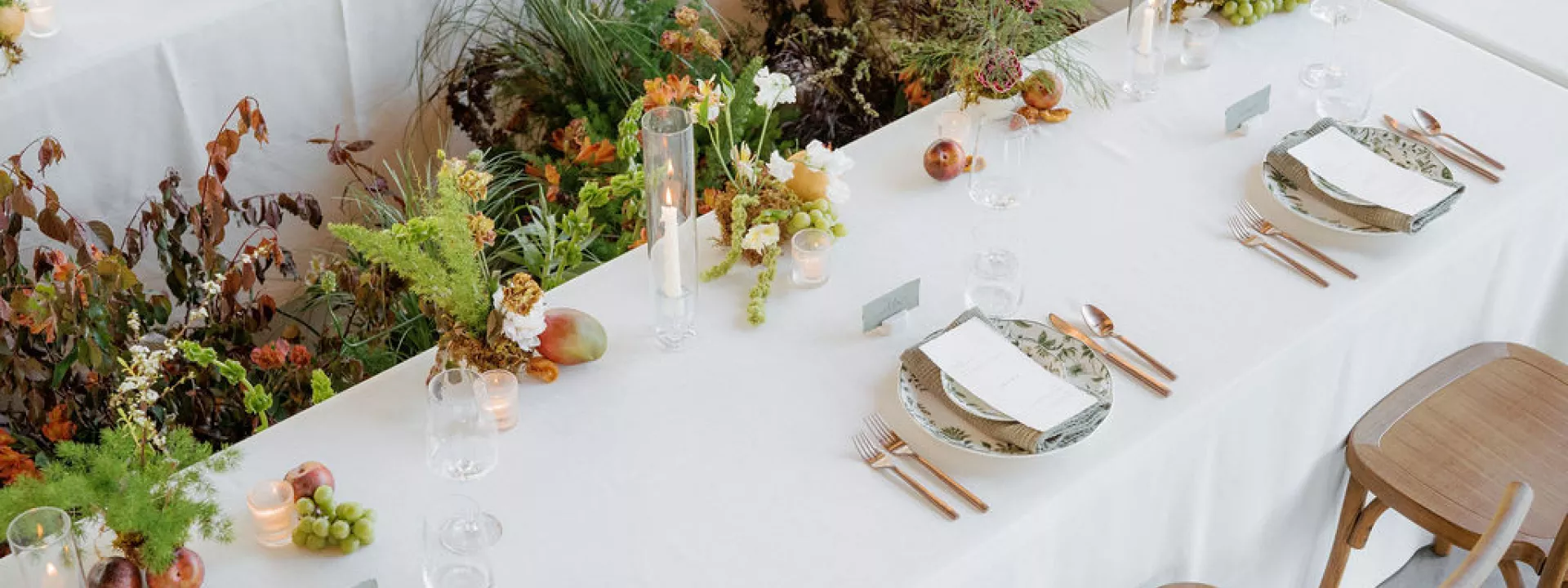 Organic florals in the middle of a rectangular table featuring simple, elegant design in glass house reception space at Woods & Co