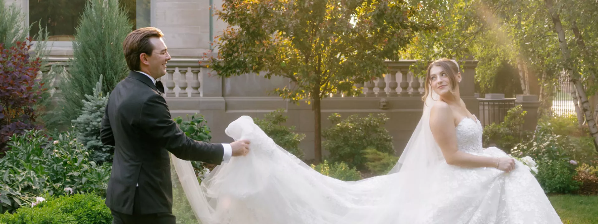 Jackson holds Grace's train as they walk across the grounds of American Swedish Institute