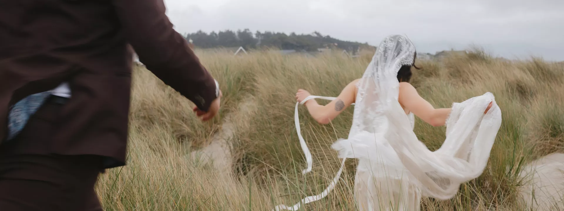Mykayla and Jake run through the beach grass during their elopement session
