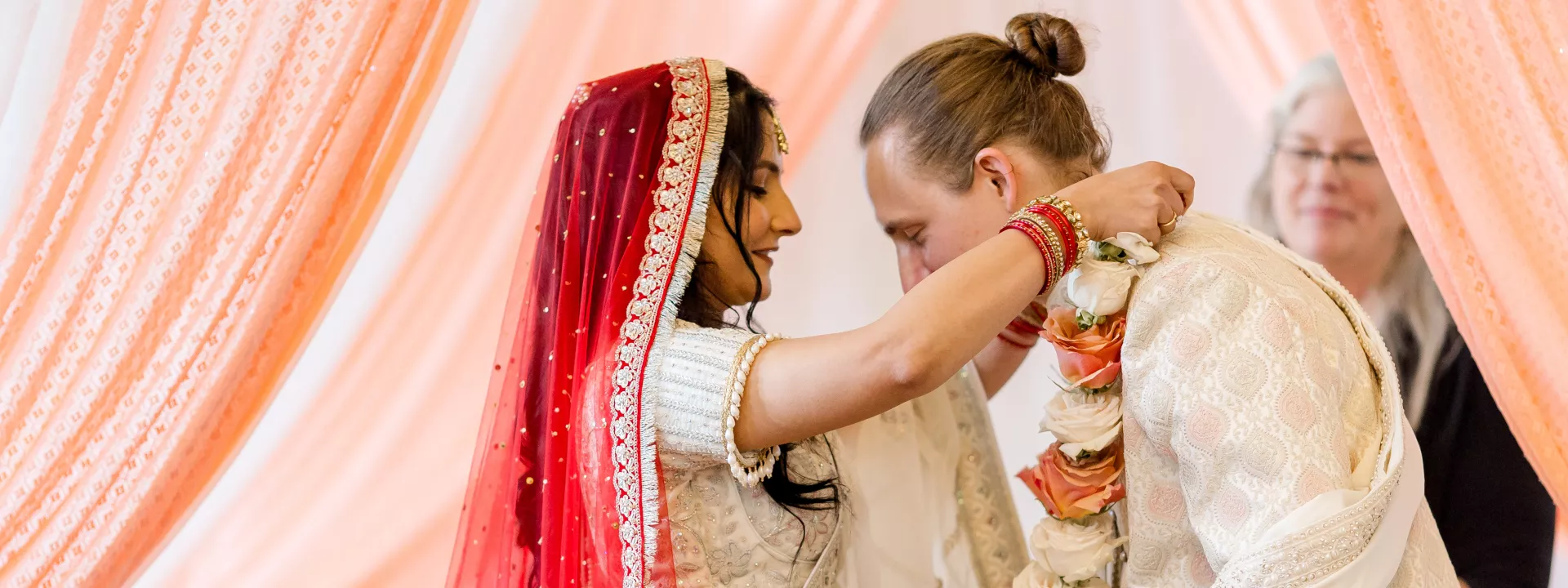 Shipra places a garland around Grant's neck during wedding ceremony