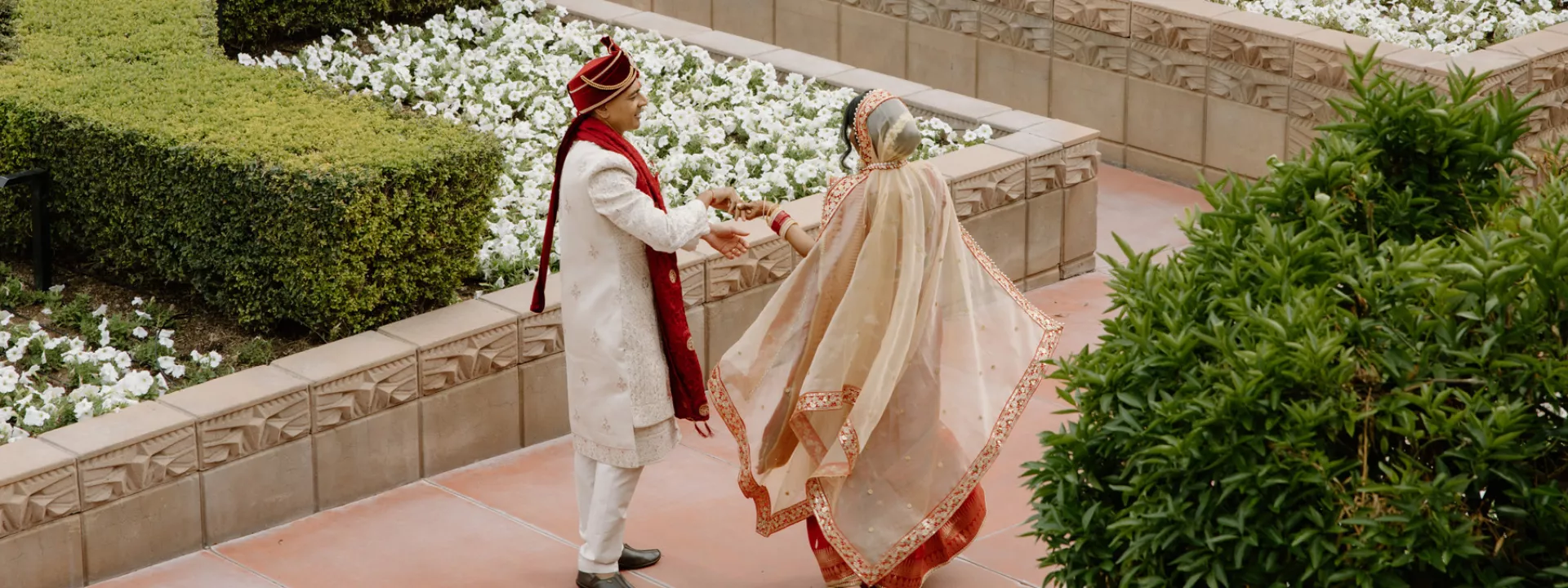 Nikita and Sahil walk hand in hand amidst the courtyard at the Arizona Biltmore on their wedding day
