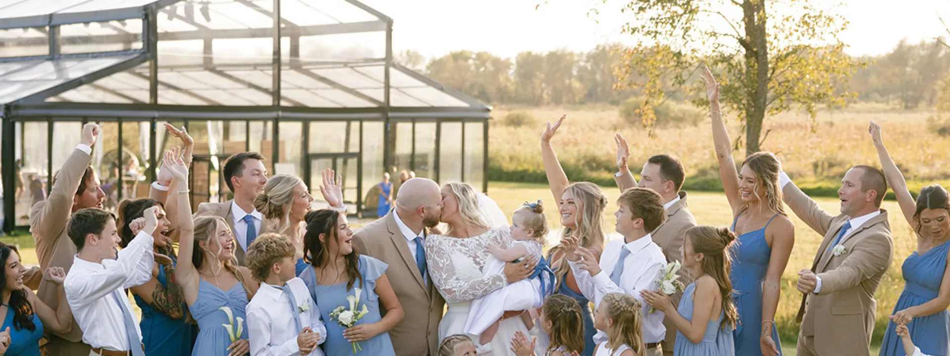 Monica and Matt kiss as their wedding party cheers on in celebration at private residence