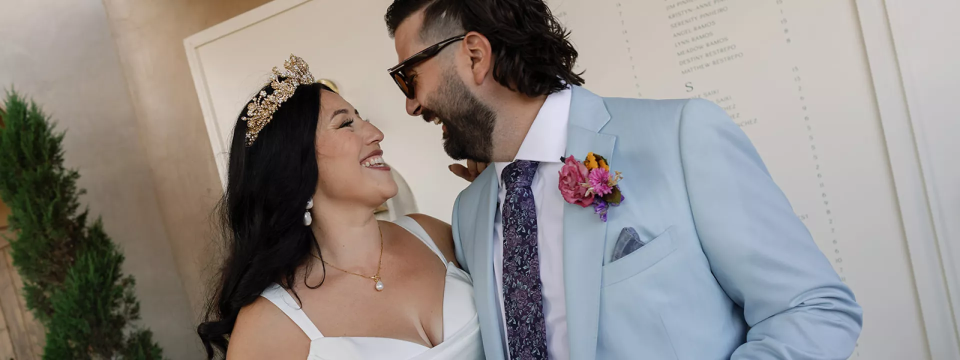 Danielle and Brandon pose in front of their custom signage at their wedding