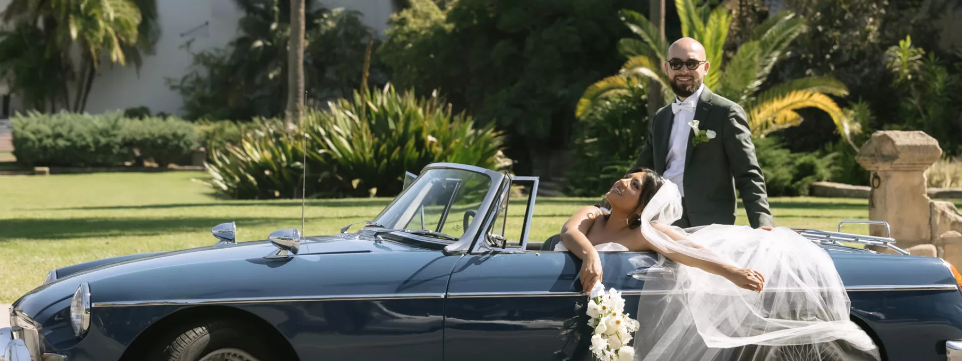 Cristabel and Martin pose in their vintage getaway car outside of the Santa Barbara Courthouse