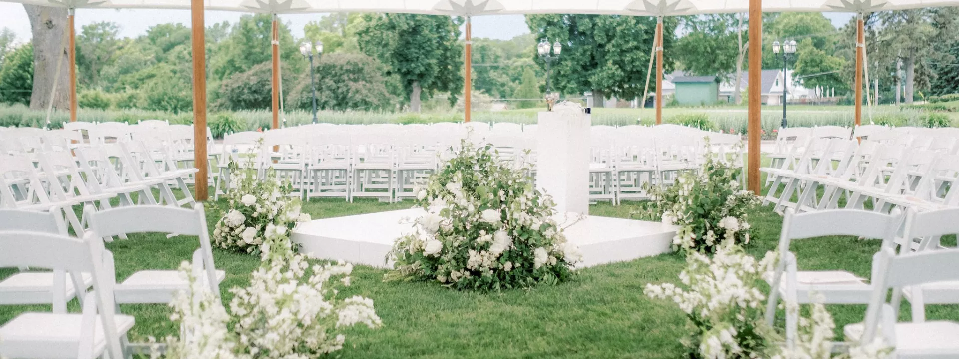 Lush tented ceremony featuring white florals at Happy Hollow Club