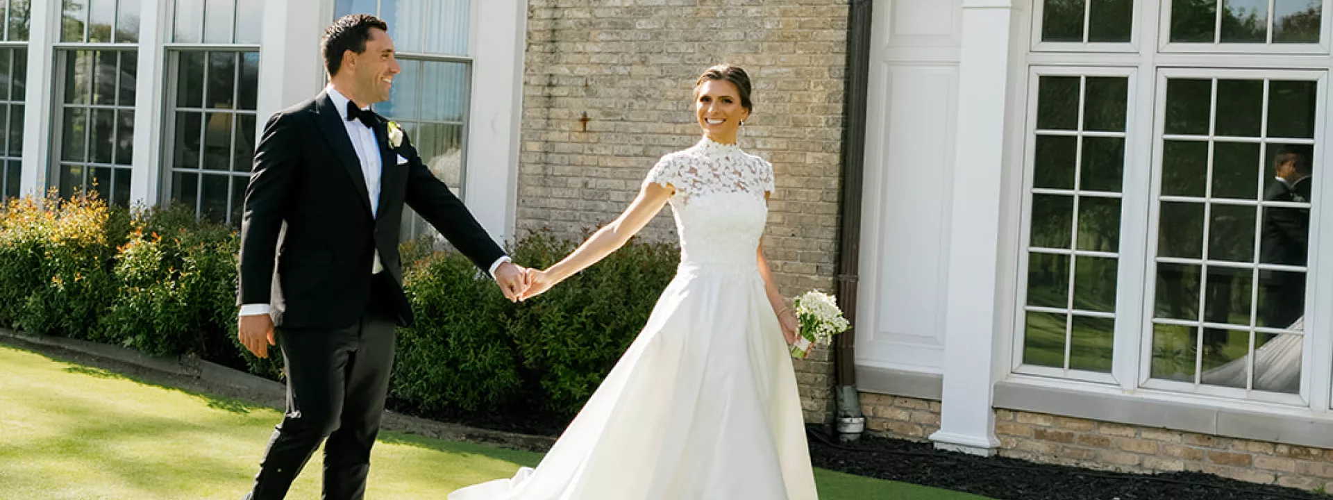 Bride and groom hold hands while walking the grounds of the Milwaukee Country Club