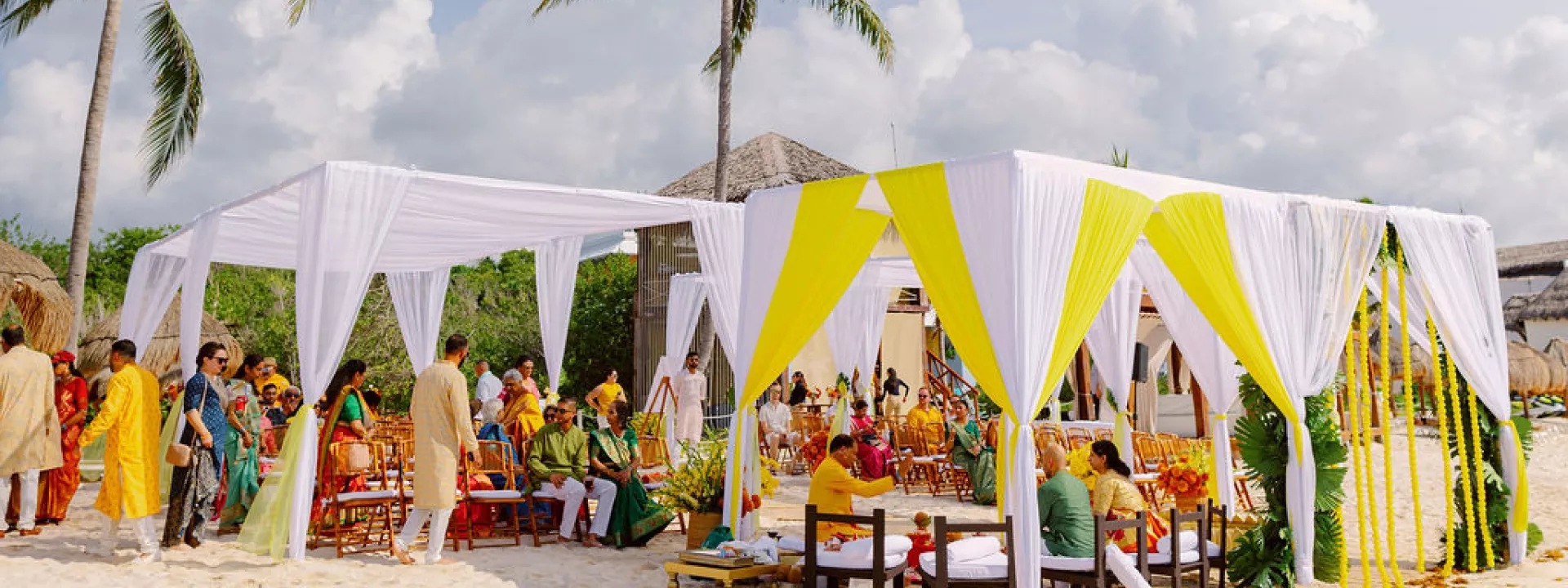Outdoor multicultural ceremony featuring bright yellow draping on the beach