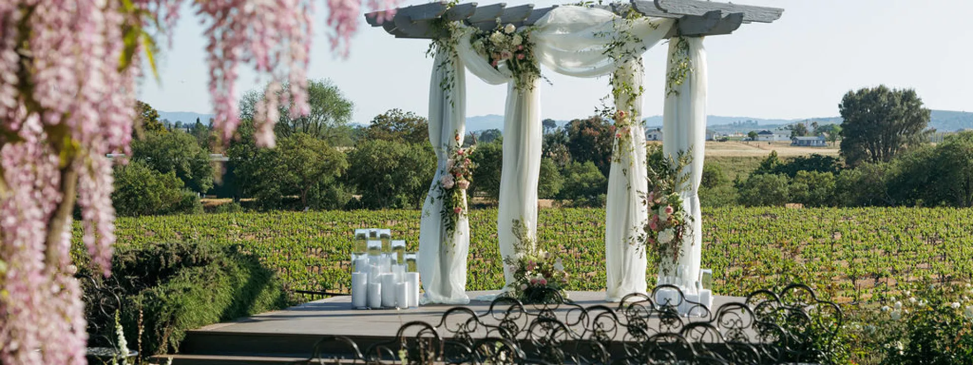 Styled ceremony scene featuring pink florals and white draping against the rolling hills of Mira Vista Estate