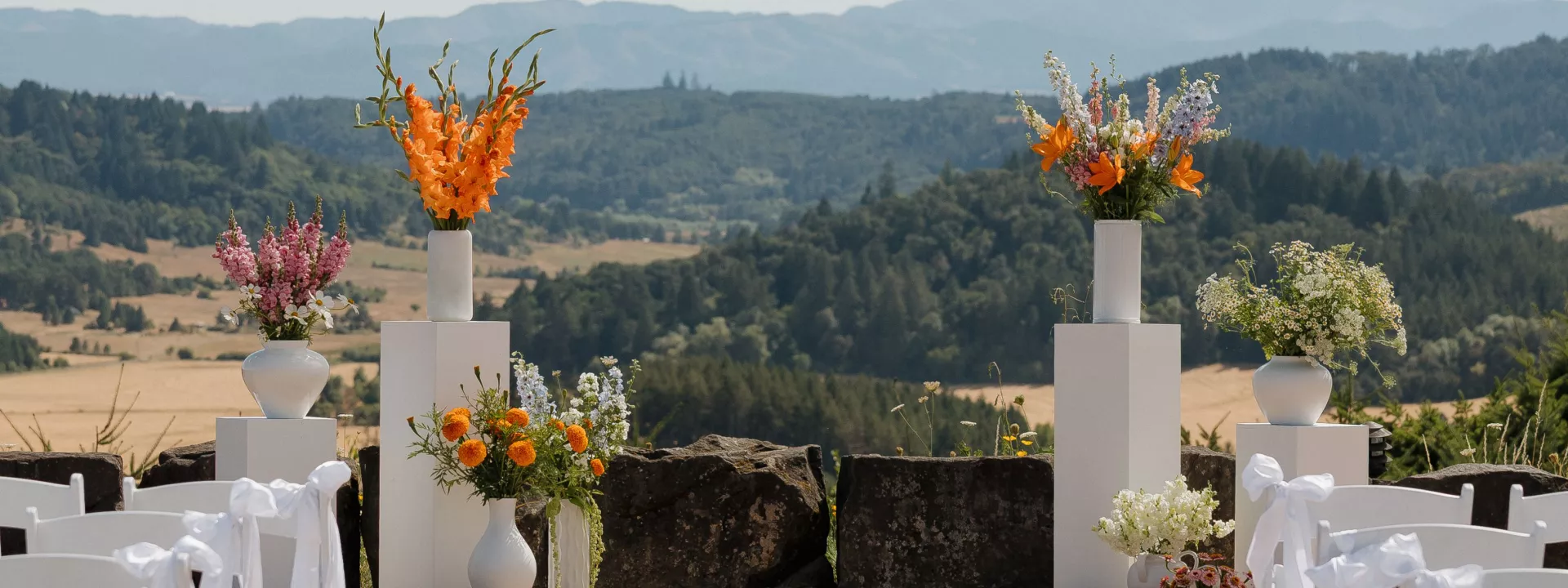 Modern altar featuring vivid blooms on podiums against the scenic views of Youngberg Hill Inn & Winery