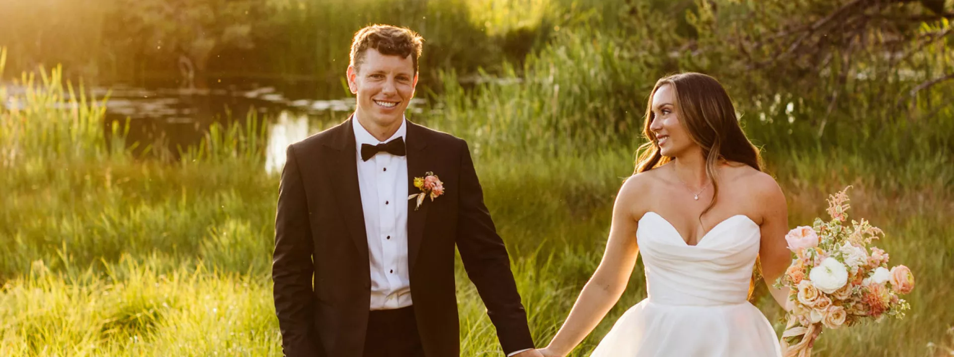 Bride and groom walk hand in hand in the golden hour light on the grounds of Sunriver Resort