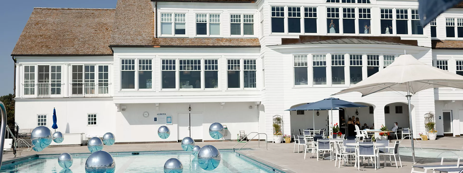Sunny shot of reception at White Bear Yacht Club featuring pool and floating balloons