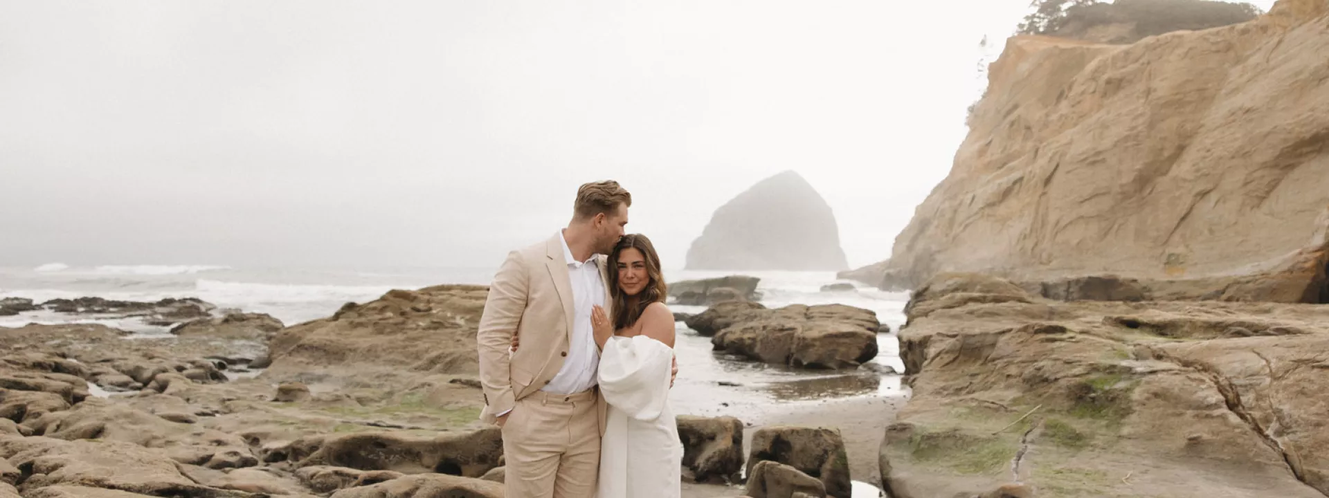 Bride and groom cozy up on the rocks of the Oregon coast