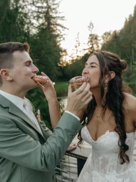 Bride and groom feed each other donuts at outdoor reception