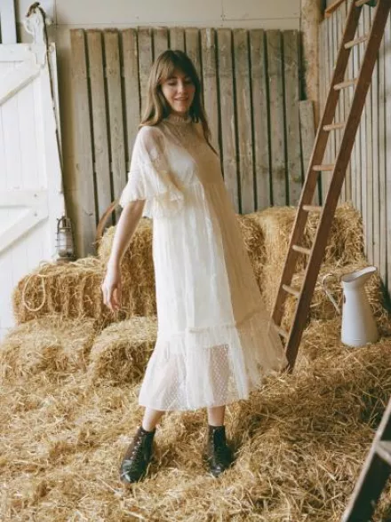 Bride in a barn wearing the Havisham dress by Joanie, a romantic Victorian-inspired wedding gown with polka-dot mesh, lace embroidery, and flounce sleeves