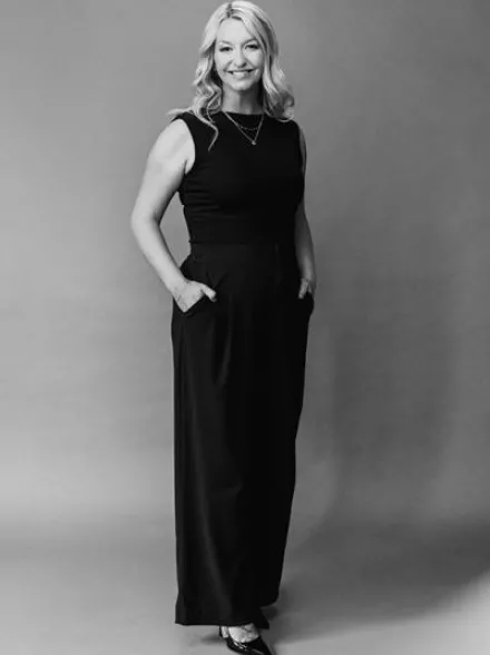 Headshot of Arizona Bride publisher Brittany O'Neill, standing wearing all black, smiling with hands in pockets