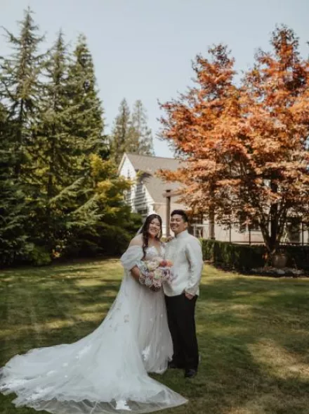 Bride and groom pose with bright foliage in the backdrop at Rock Creek Gardens